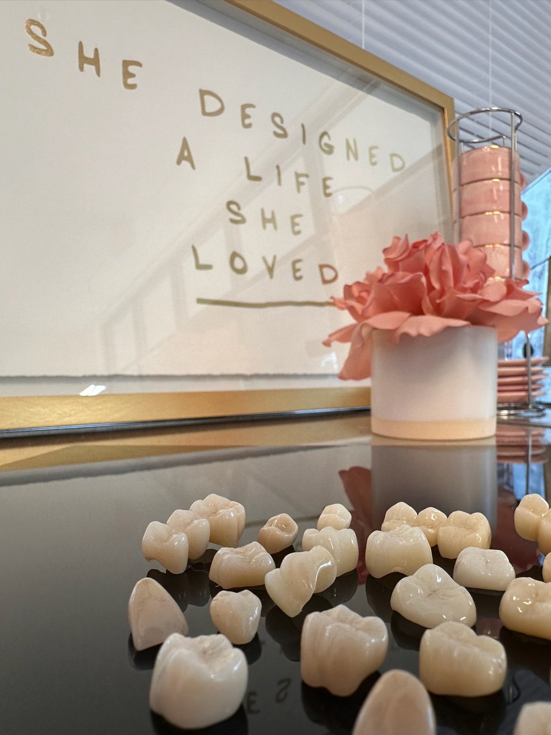 A framed print reading 'She designed a life she loved' hanging above the mirrored bench, with finished crowns laid out beneath it